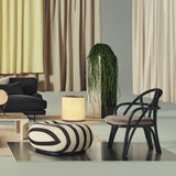 A black bentwood lounge chair with a rounded back and taupe padded seat beside a striped ottoman