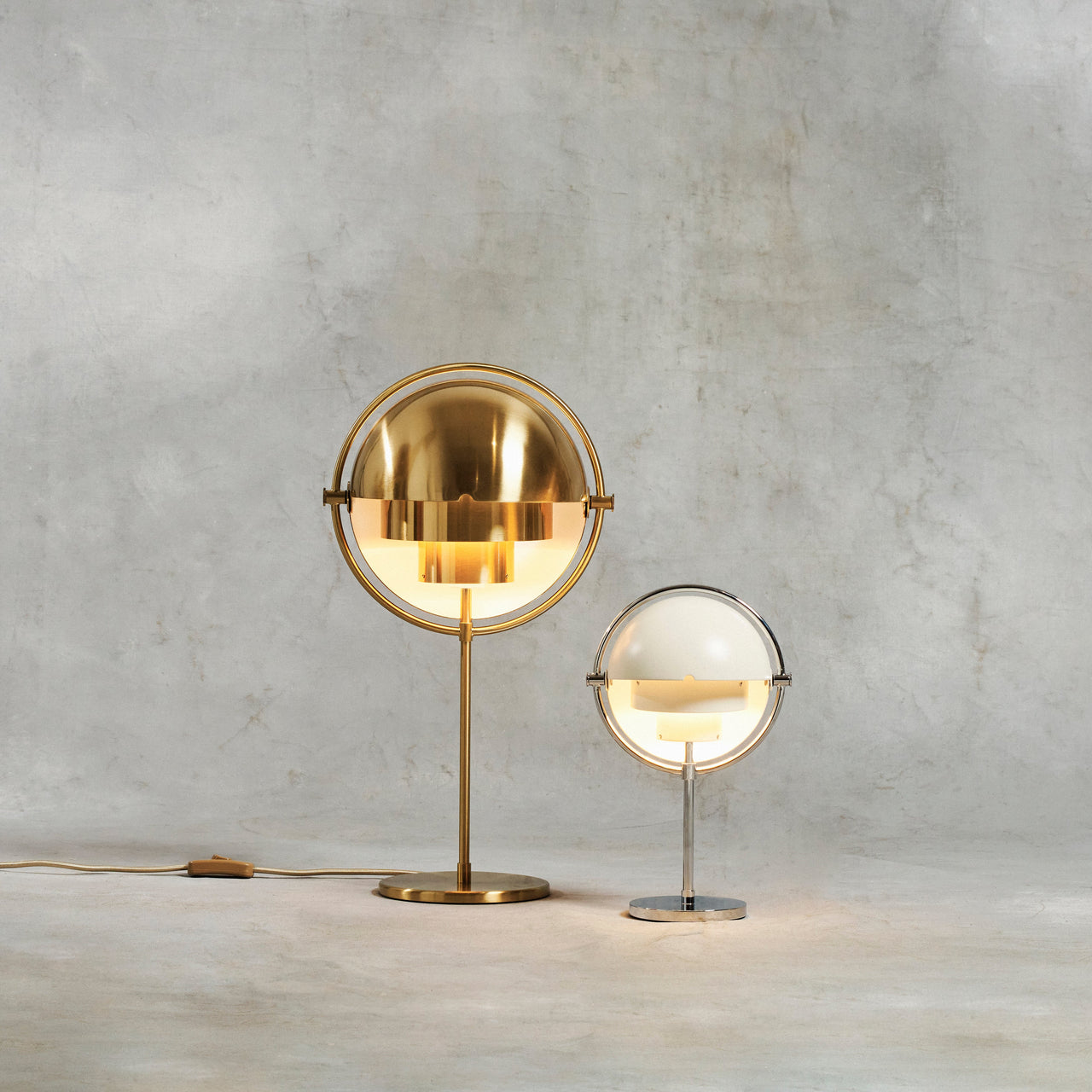 Two glowing table lamps with half-dome shades, one tall in polished brass and a smaller one in white and chrome