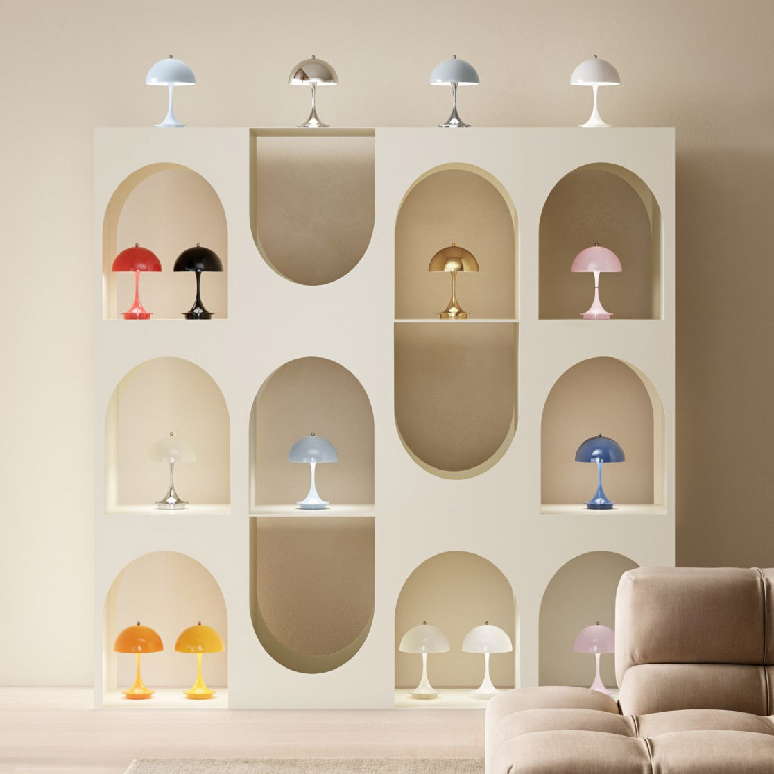 Mushroom-shaped table lamps in many colours on a cream shelving unit with arched niches, beside a beige sofa