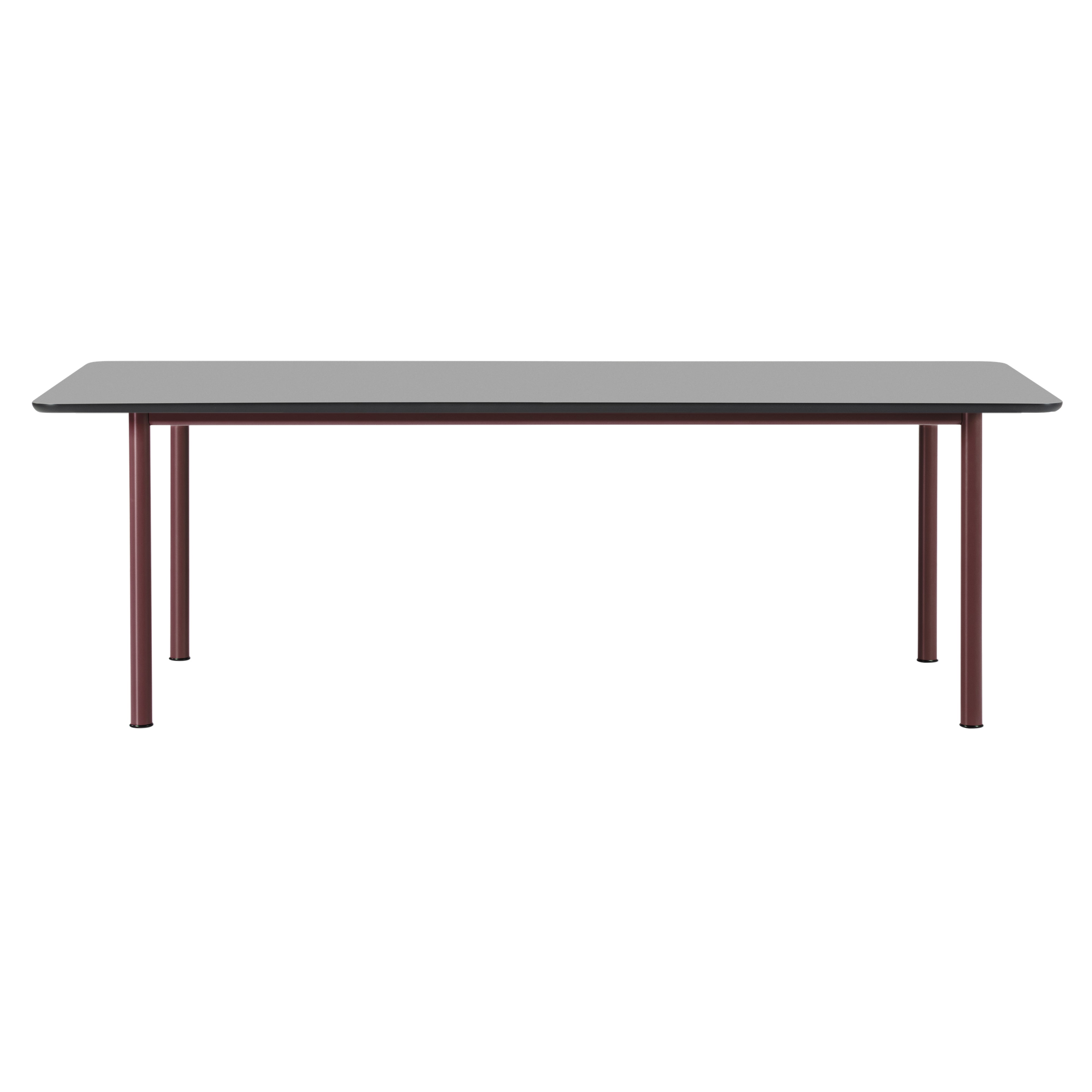 A rectangular table with a grey top and rounded corners on four slim burgundy metal legs