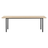 A rectangular dining table with a light oak top, rounded corners and four slim black tubular legs