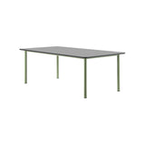 A rectangular table with a flat grey top and slim round sage green metal legs