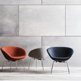 Three rounded bowl-shaped lounge chairs in rust orange, pale grey and navy on slim chrome legs