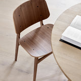 Overhead view of a walnut wooden chair with a curved back beside a round light oak table