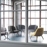 Rounded lounge chairs in yellow and grey fabric on light wooden legs, seen through a paned window