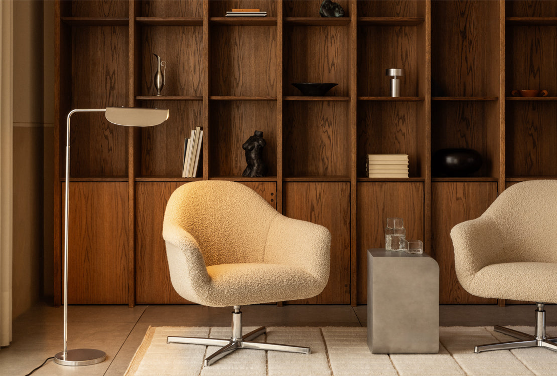 Modern interior with beige armchair, floor lamp, and wooden shelves.