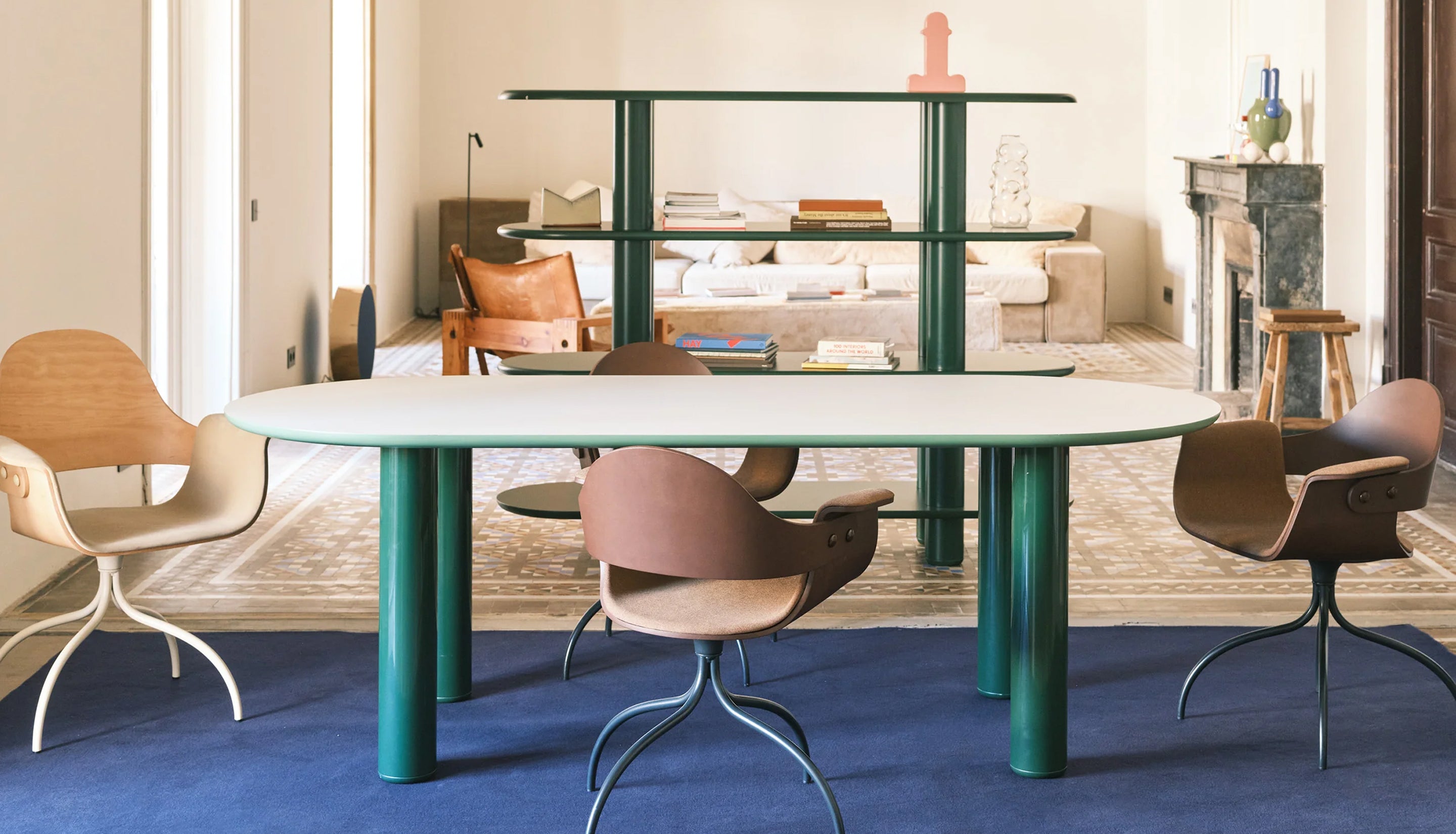 Modern dining room with a round table and colorful chairs on a blue carpet. Featuring the Eclipso line from BD Barcelona.