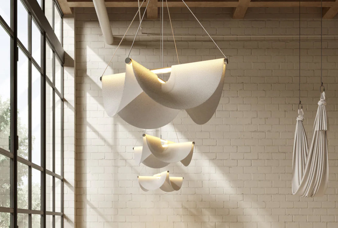 Draped white lighting in room with large windows and white brick