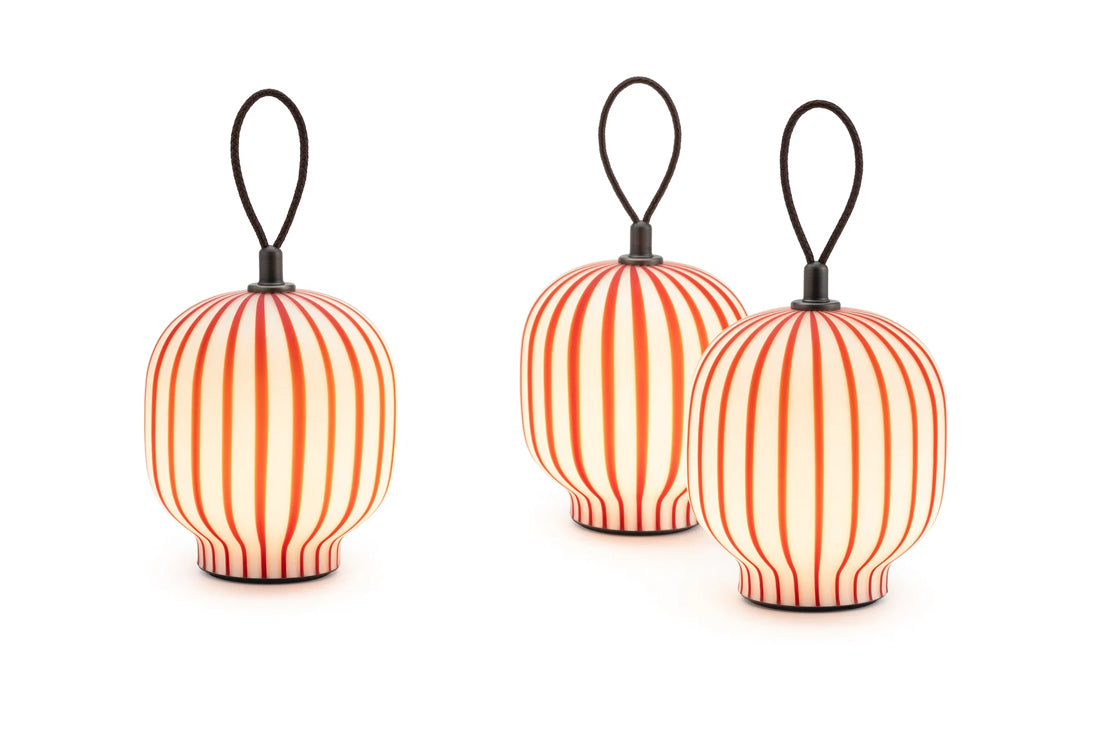 Three small hanging lanterns with black loop handles, featuring vertical red and orange stripes and glowing warm light, shown on a white background.