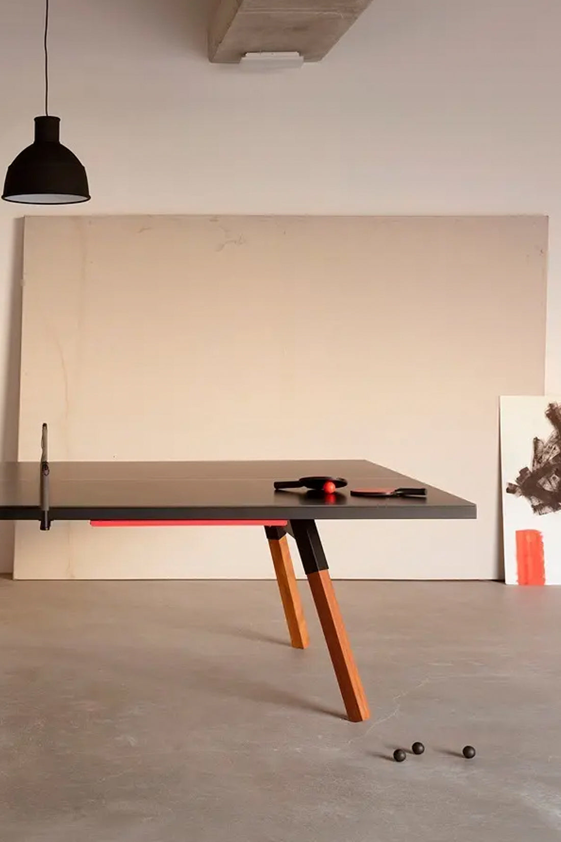 Modern ping pong table with orange legs in a minimalistic room.