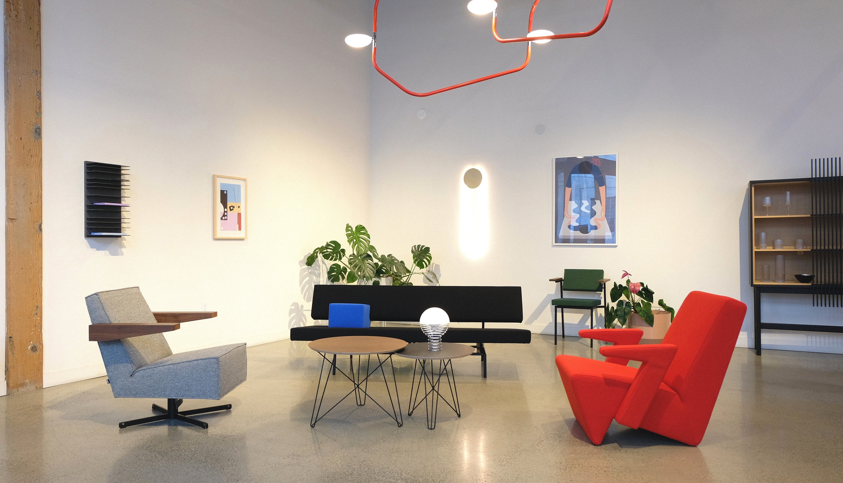 Showroom with modern furniture, decor, and lighting on display with white walls and concrete floor. 