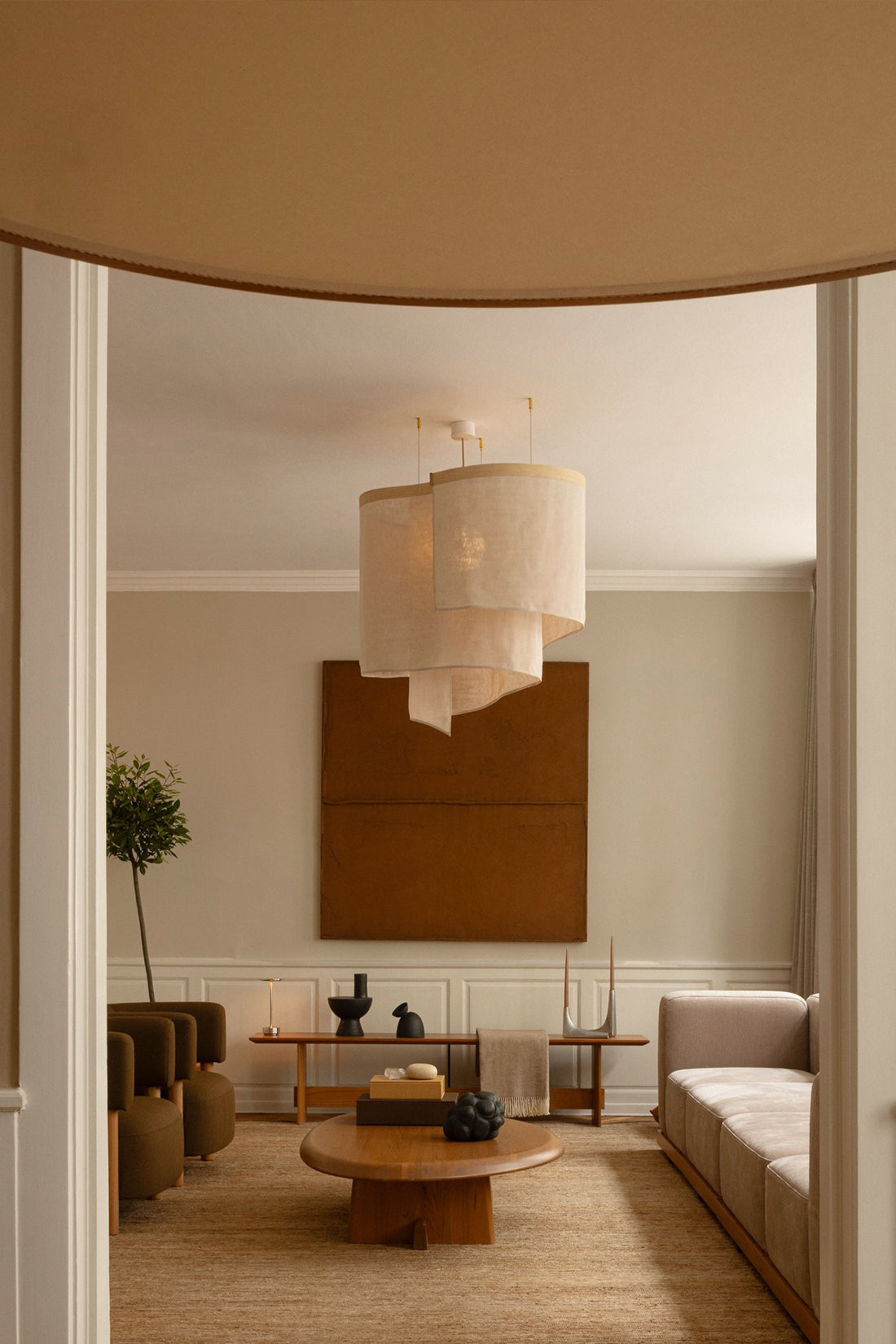 Modern living room with neutral tones, a chandelier, and a painting.