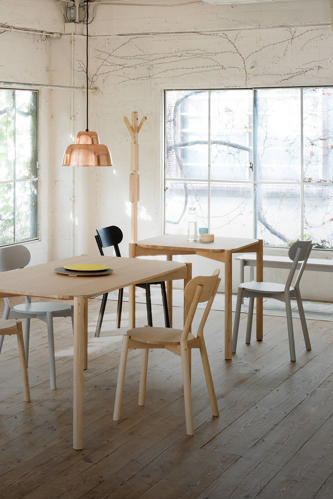 Modern dining area with wooden tables and chairs in a bright room.