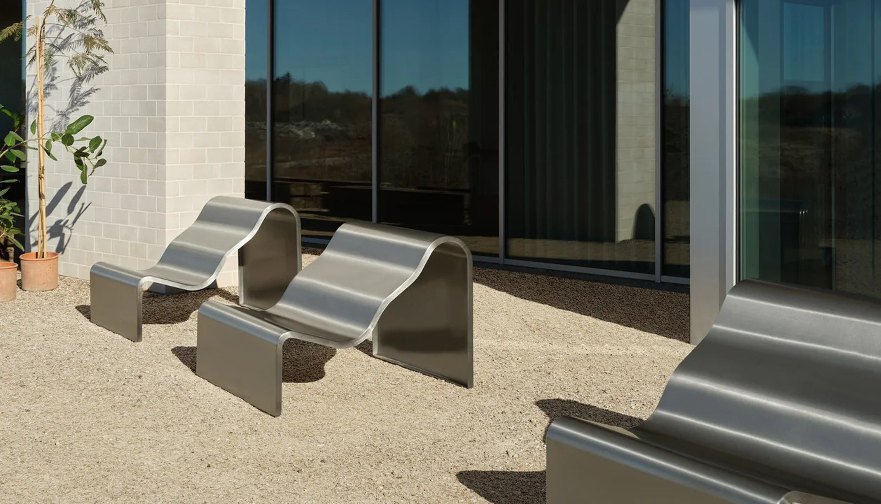 Modern outdoor furniture set with curved metal chairs in front of a building.