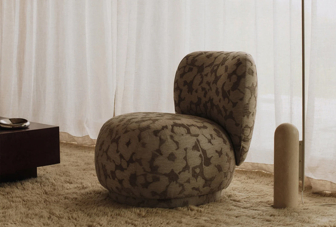 Patterned chair in a room with curtains and a small table.