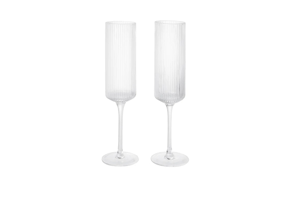Two white fluted champagne glasses on a white background