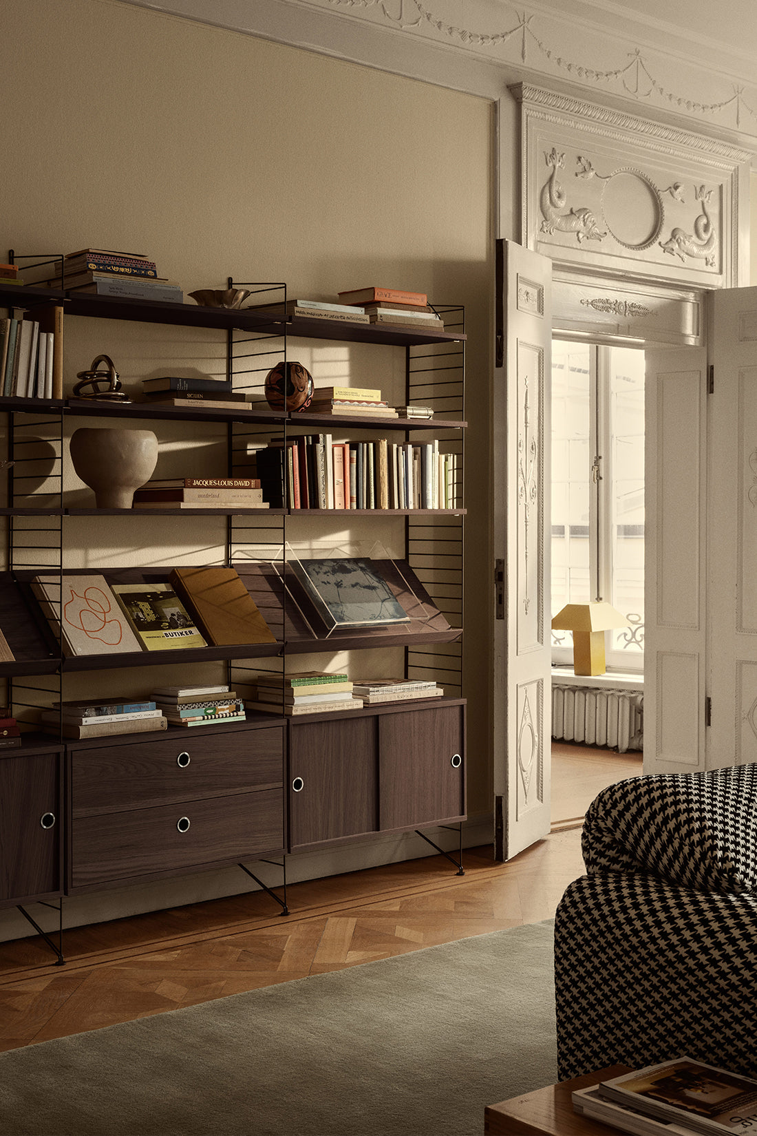Living room with a bookshelf filled with books and decorative items, a sofa, and a large mirror.