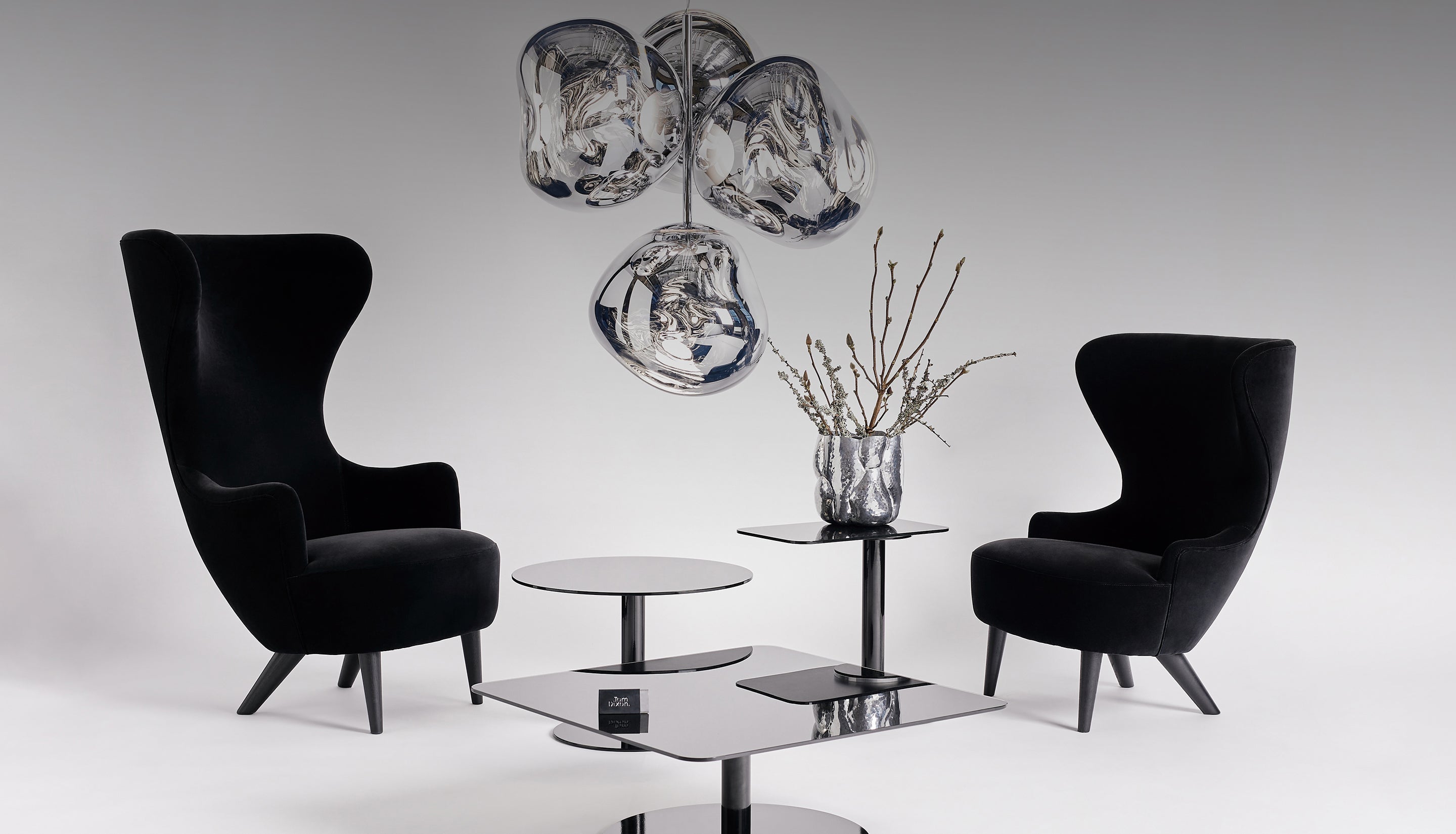 Modern interior with black armchairs, tube tables, and melt chandelier in silver.