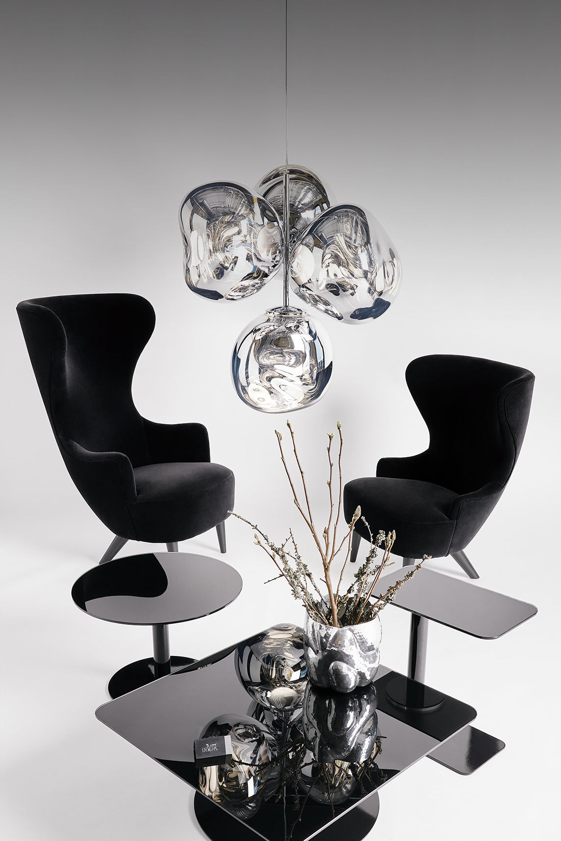 Modern interior design with black chairs, a glass table, and a decorative chandelier.