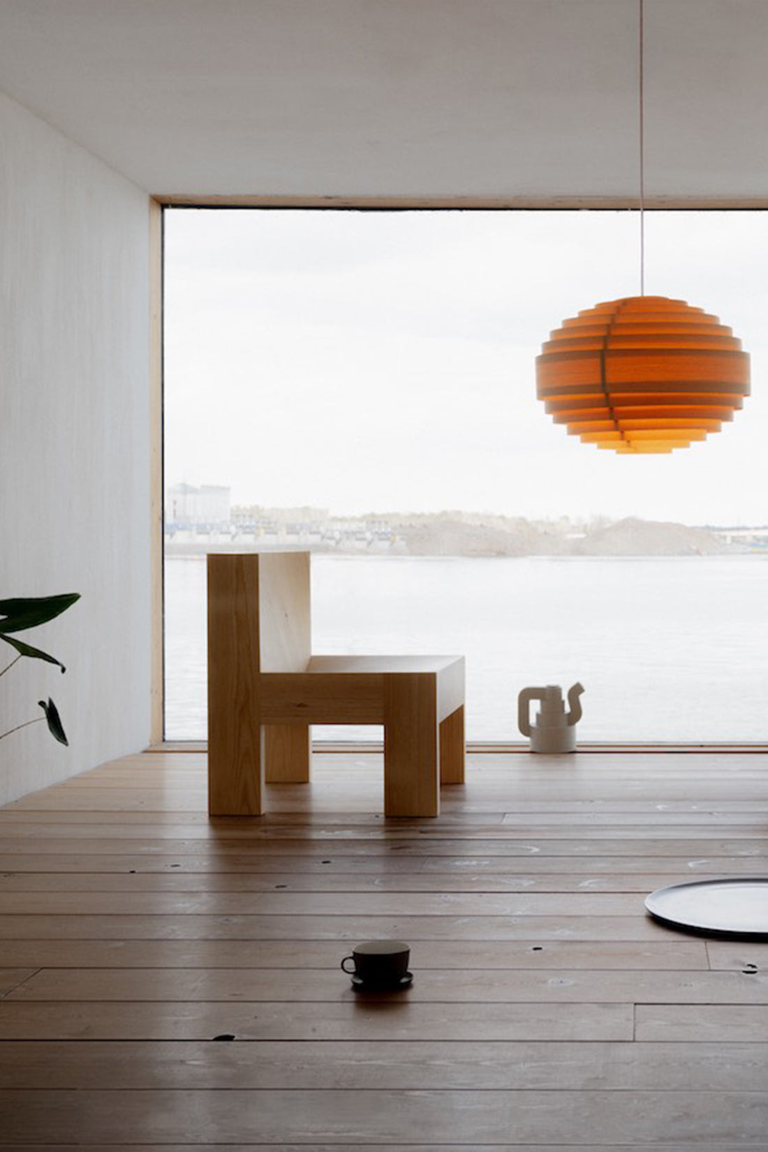 Modern interior with wooden floor, chair, and pendant light.