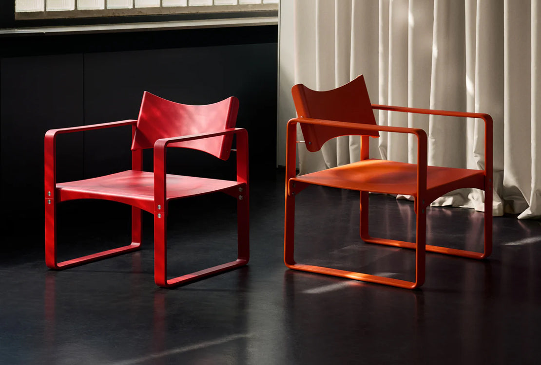 Two chairs in a room with a dark floor and light-colored curtains.