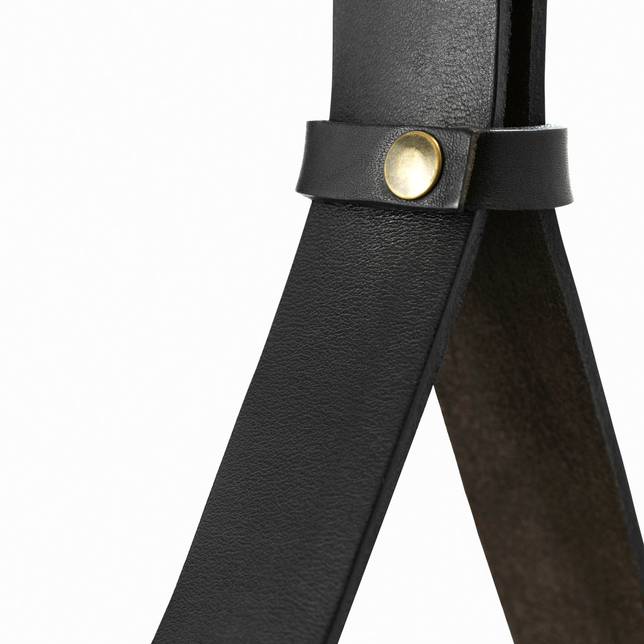 Close-up of two black leather straps crossing, held together by a small brass snap fastener
