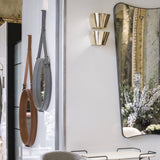 Two round mirrors with leather strap hangers beside a tall dark-framed mirror and brass wall lights