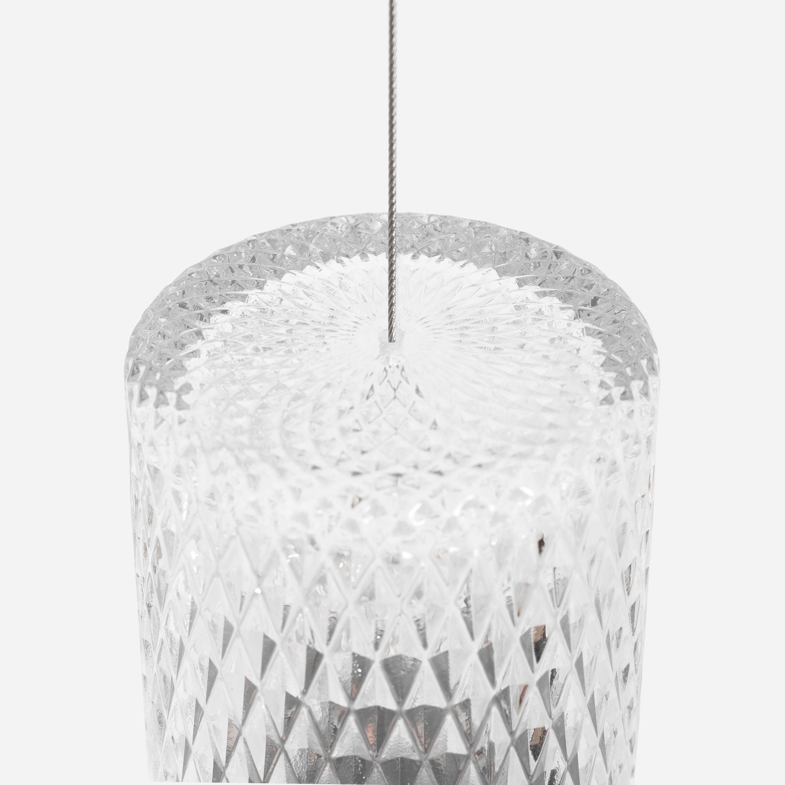 Close-up of a clear cylindrical glass pendant with a diamond-cut pattern, hung from a thin steel cable