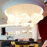 A cluster of glowing white woven globe pendants hangs in a round ceiling recess above lounge sofas